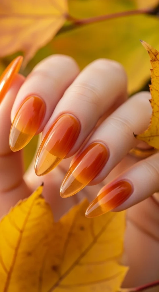 21 Fall Nails Inspiration 2026! Chic Trendy Autumn Manicures 15 Sheer amber jelly almond nails glowing in soft backlight with blurred autumn leaves behind, retro warm look