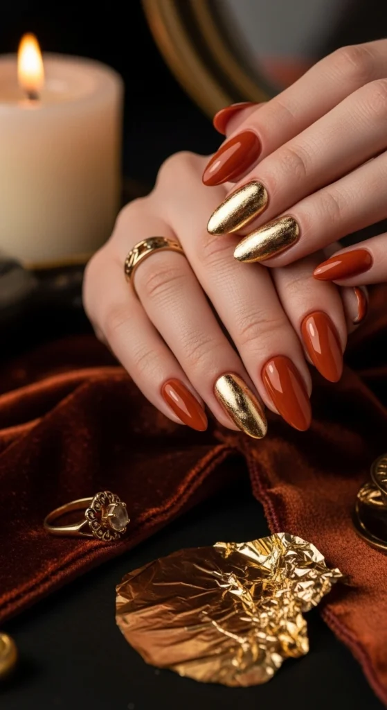 Close-up of almonds shaped burnt-orange jelly nails with gold foil over velvet scarf.