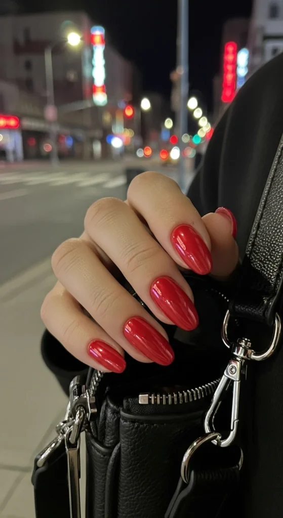 Candy-apple chrome almond nails in POV shot reaching for black crossbody bag.