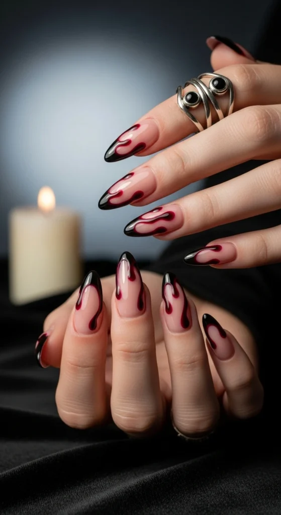 Nude almond nails with glossy crimson red drip-effect French tips, gothic glam Halloween nails. 