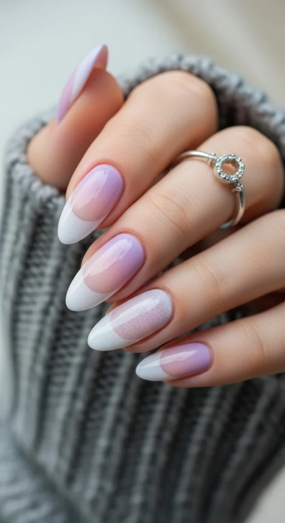 Close-up of almond nails in lavender-to-white French ombré fade with a frosty sheen.