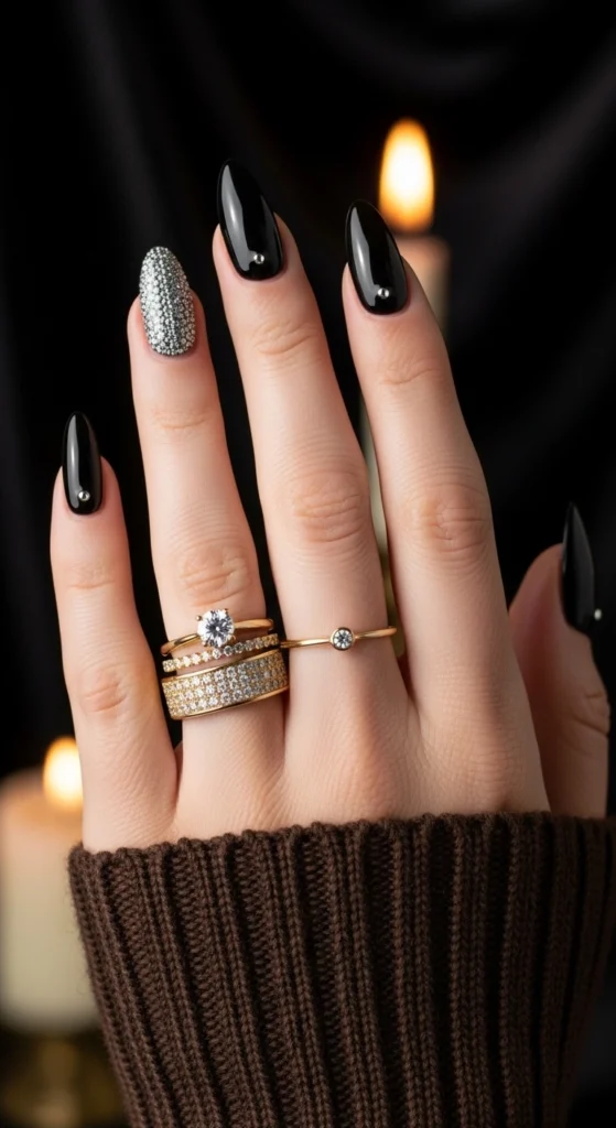 21 Fall Nails Inspiration 2026! Chic Trendy Autumn Manicures 2 Glossy jet-black almond nails with sparkling crystal accents against softly blurred black silk fabric, editorial close-up.