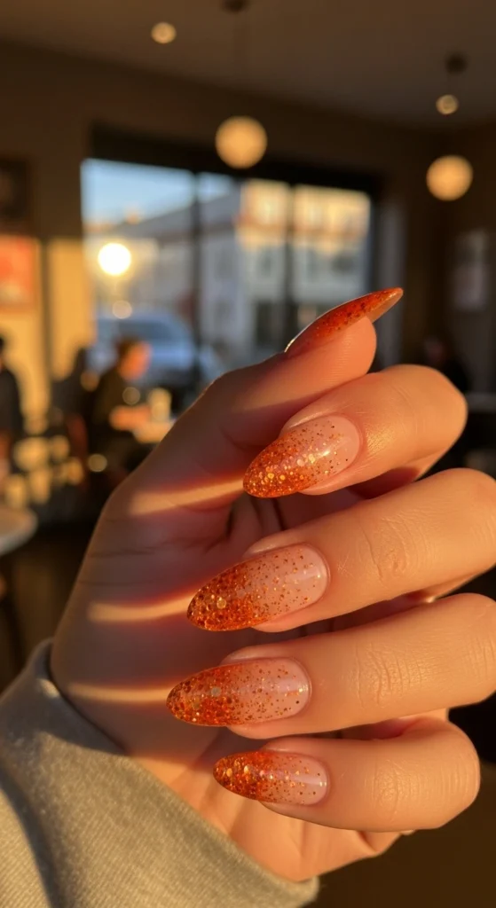  Almond nails with orange glitter fade in cozy café