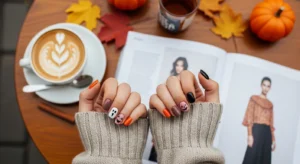 Simple Halloween nails with ghost and pumpkin art and more, on a flat themed table