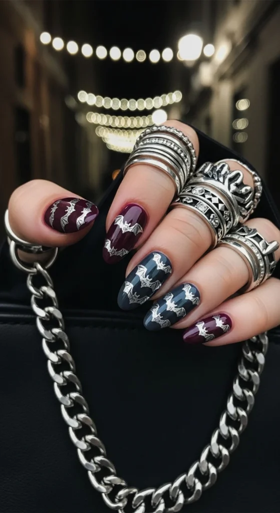 Cinematic close-up of short round velvet plum cat-eye nails with silver bat designs, shot in a street-style moody alley.