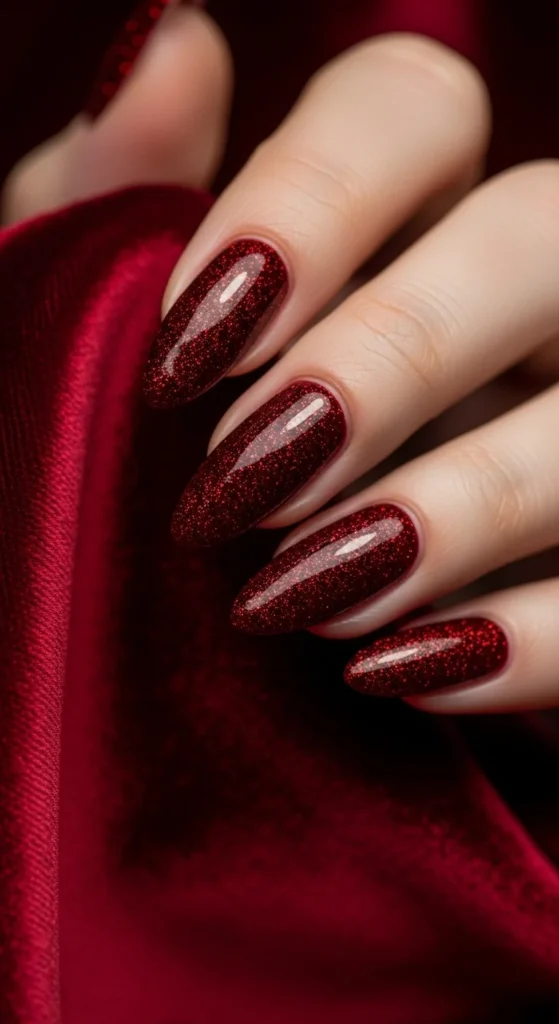 Wine red nails with sparkling glitter accent.