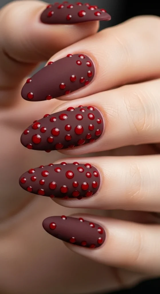Matte burgundy nails with glossy red velvet-style dots.