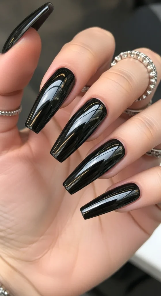 Glossy black chrome nails with a mirror-like metallic finish, reflecting light for a bold, futuristic Halloween look.