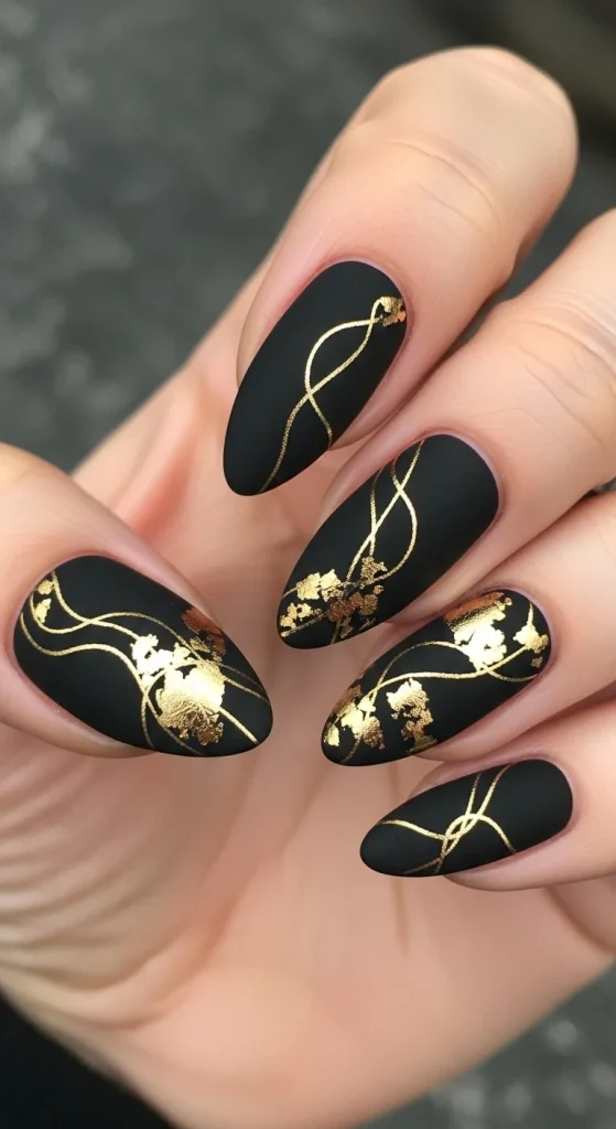 Almond nails matte black with gold foil details.