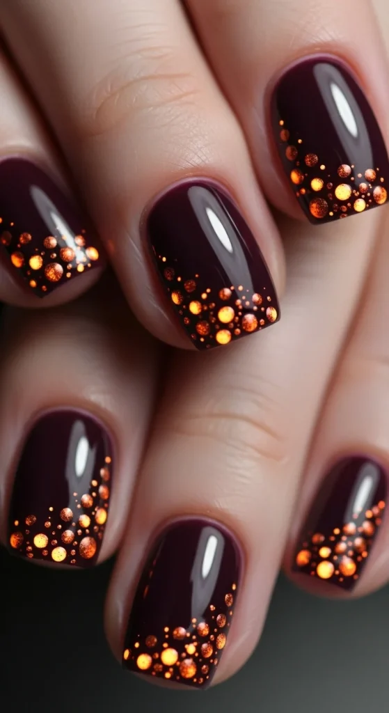 Dark plum nails with glowing copper and orange dots.