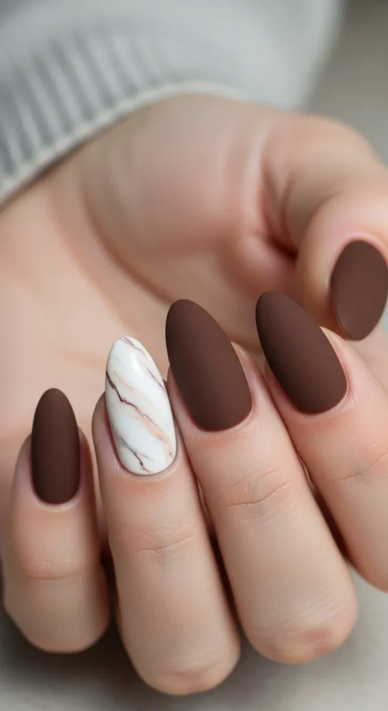 25 Fall Matte Nails 2026 | Trendy Autumn Colors & Velvet Chic Ideas 23 Matte chocolate nails with one marble accent nail in white and beige.