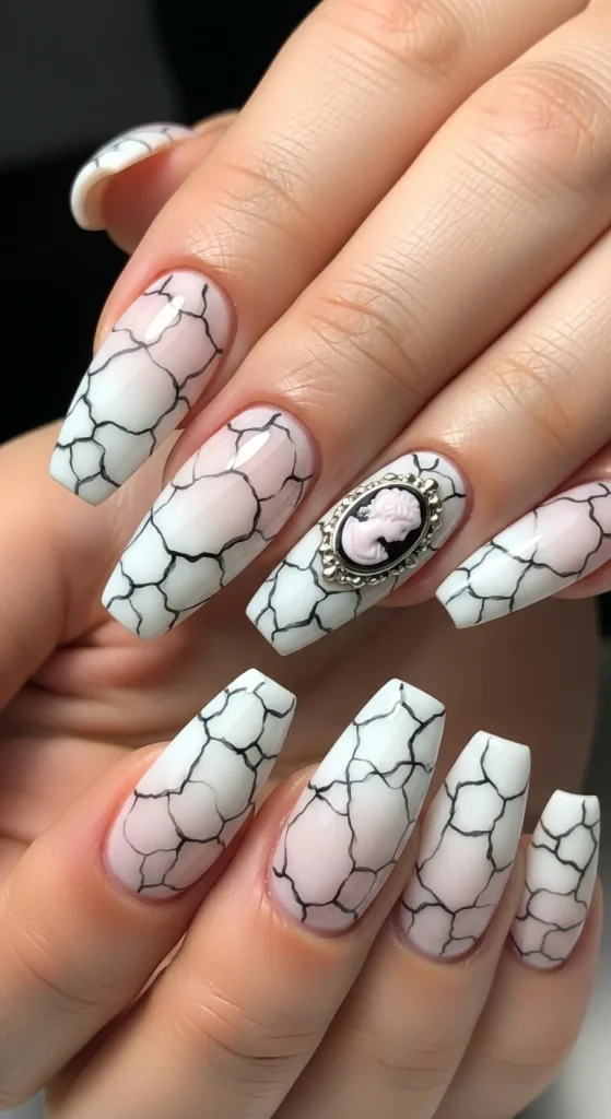 : Almond nails in soft white with blush base and fine gray-black crack patterns