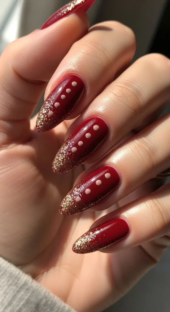 Cranberry red nails with gold sparkle and nude dots.