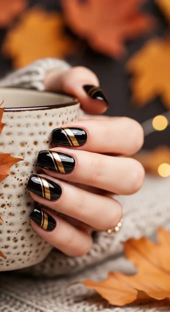 Black Fall Nails 2026: 19 Trendy Designs You’ll Love 11 Glossy black nails with diagonal gold stripes, fall aesthetic.