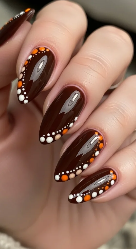 Espresso nails dotted with cream and pumpkin orange dots.