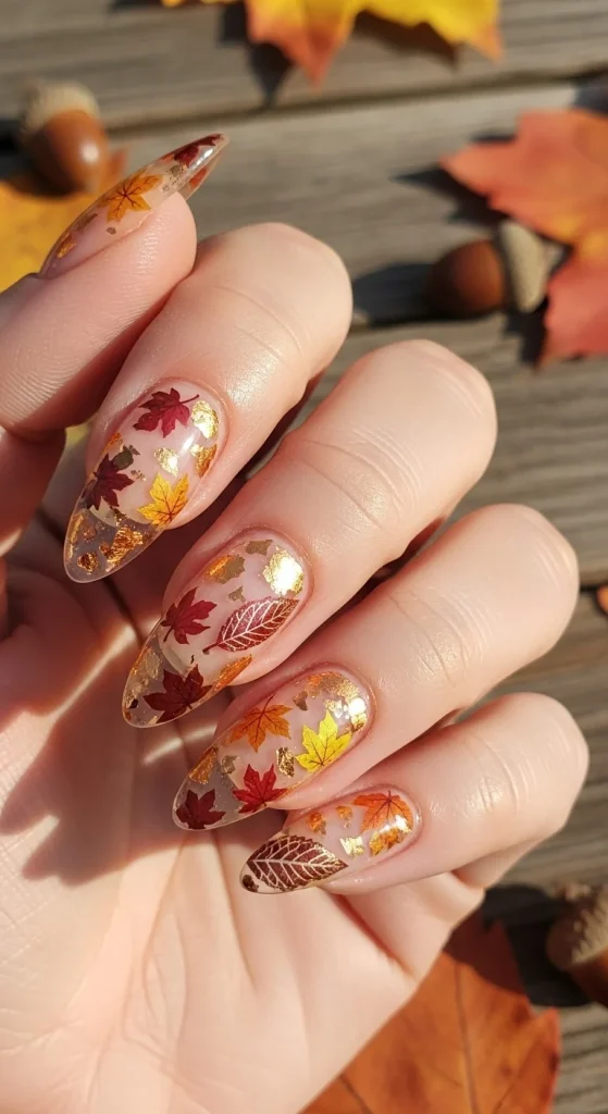 Pressed leaf encapsulation fall nails — clear resin with tiny autumn leaves and metallic veins.