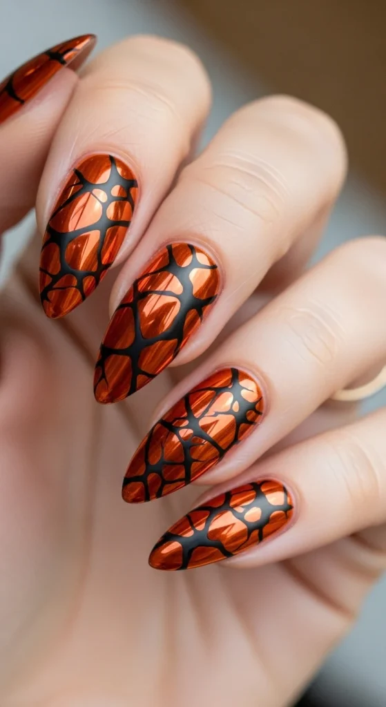 Chrome pumpkin-orange nails with matte black shattered crackle overlays