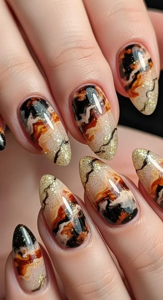 Almond tortoiseshell nails with gold glitter accents.