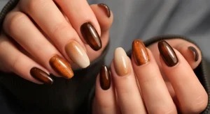 Flat lay of aesthetic fall gel nails featuring pumpkin chrome, latte ombré, and cinnamon brown aura designs arranged on a neutral background.