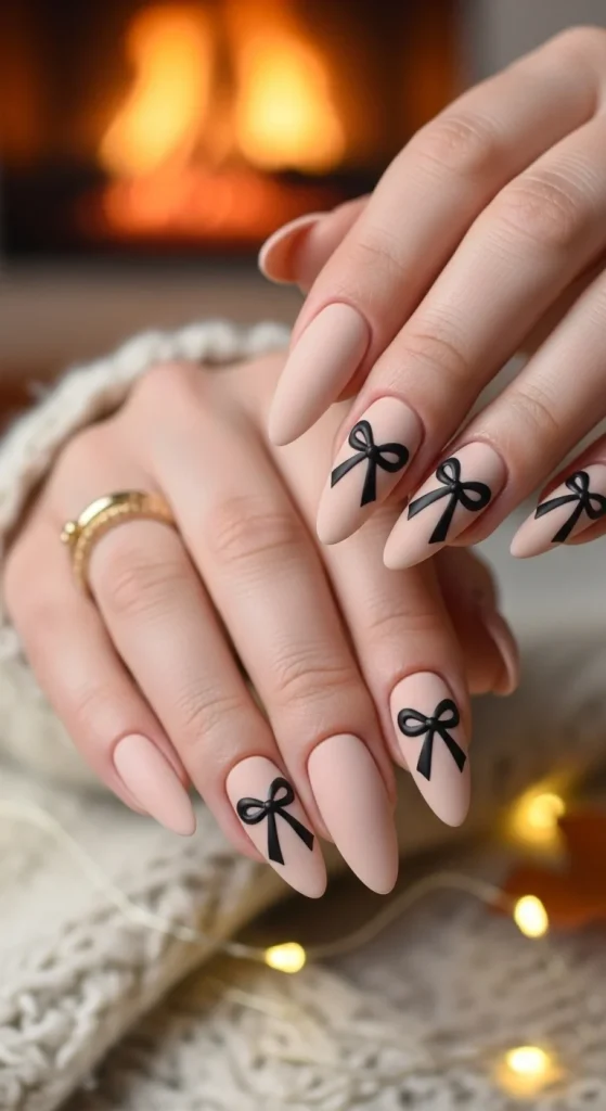 nude nails with black ribbon bow accents.