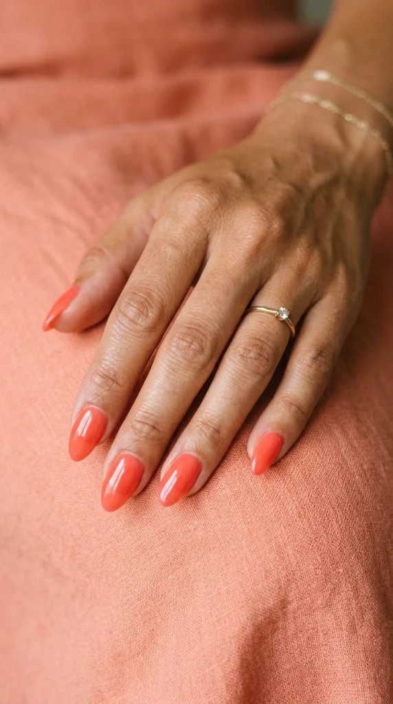 Summer Nail Colors 2026: 25 Trending Shades to Wear This Season 9 Vibrant coral almond nails with a glossy finish, a flattering summer nail color trend for 2026.