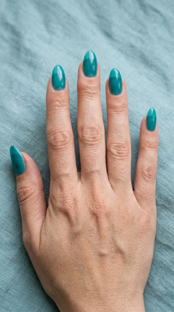 Summer Nail Colors 2026: 25 Trending Shades to Wear This Season 19 Glossy sea glass teal almond nails with a translucent finish, a tropical blue-green summer nail color trend for 2026.