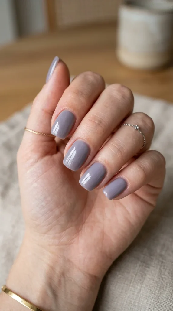 Short squoval nails with glossy smoky lavender polish featuring elegant gray-lilac undertones.