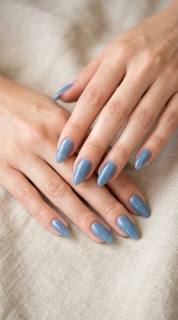 Summer Nail Colors 2026: 25 Trending Shades to Wear This Season 7 Soft washed denim blue almond nails with a glossy finish, a wearable blue summer nail color trend for 2026.