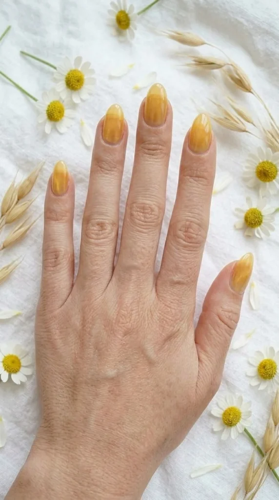 Close-up of glossy butter yellow almond nails, one of the most popular summer nail colors for 2026.