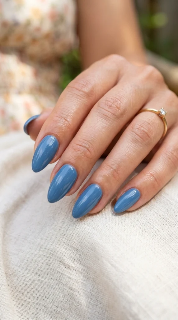 Close-up of glossy cornflower blue almond nails, a soft airy summer nail color for 2026.