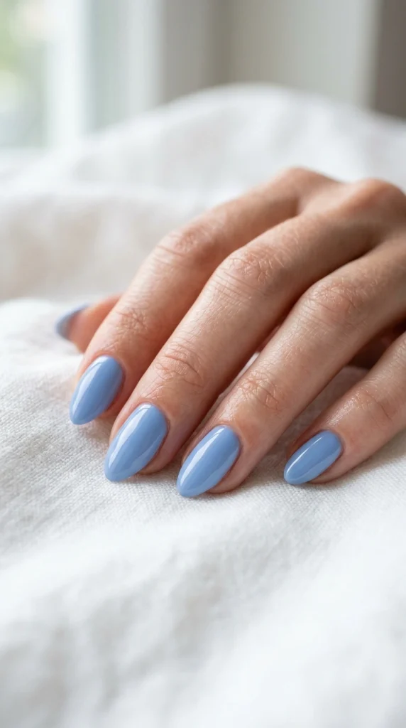 Close-up of glossy sky blue almond nails in a simple monochrome summer manicure.