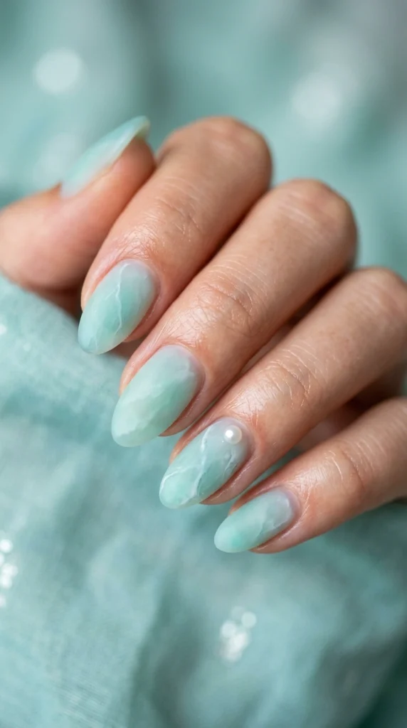 Close-up of frosted aqua and mint sea glass almond nails.
