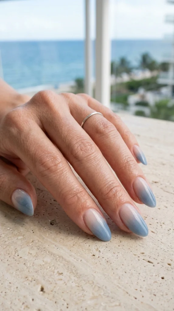 Denim blue ombre almond nails with a soft ocean-inspired gradient for a classy coastal summer manicure.