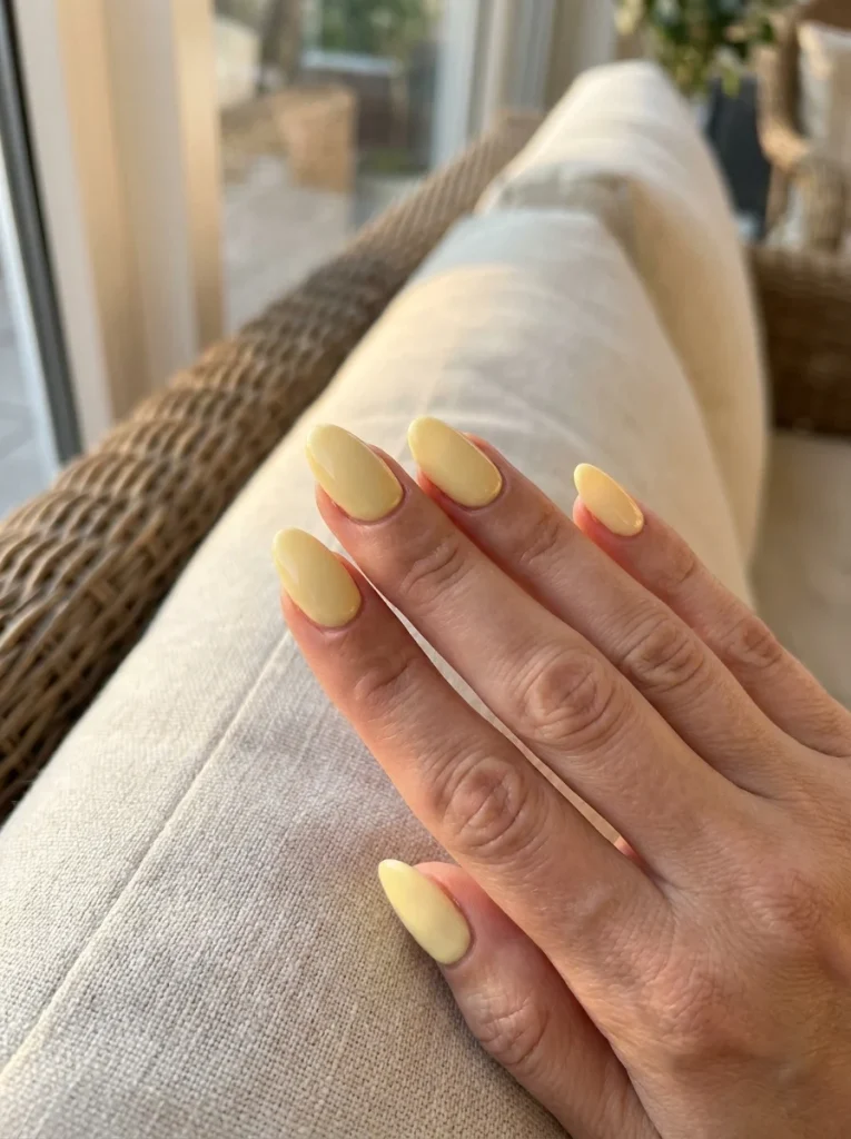 Butter Glow manicure with creamy butter yellow nails and an ultra-glossy finish on medium almond-shaped nails for a chic summer look.
