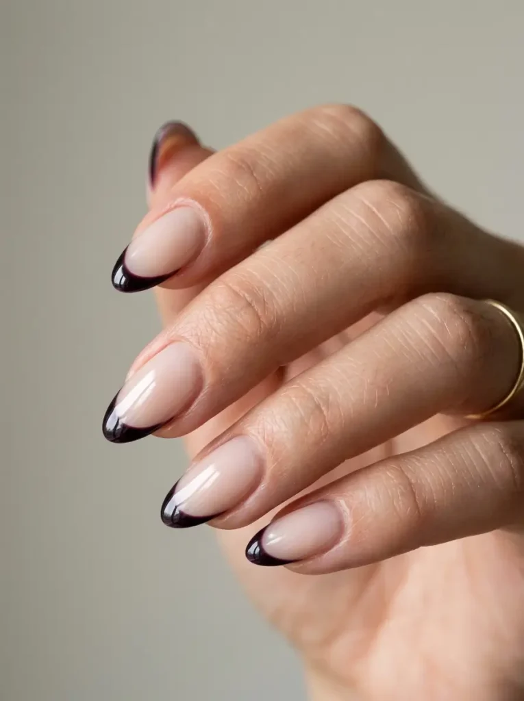 Close-up of almond nails with a sheer milky base and ultra-thin glossy blackberry French tips.