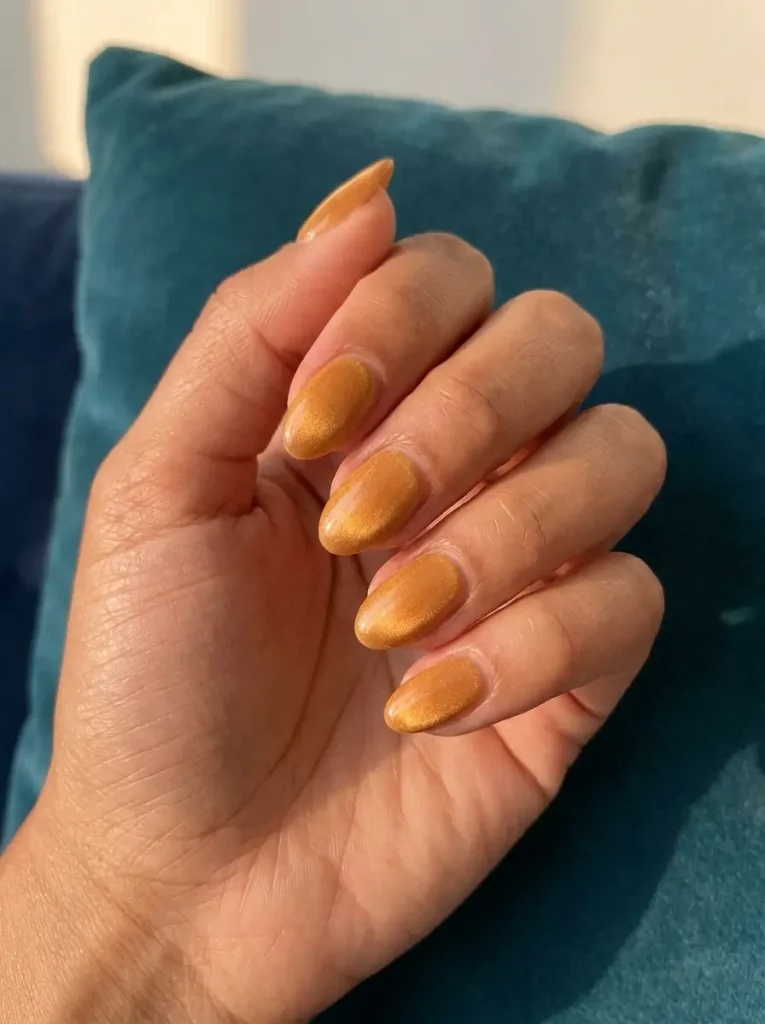 Short almond nails in an all-over amber velvet cat eye gel finish on a medium skin tone