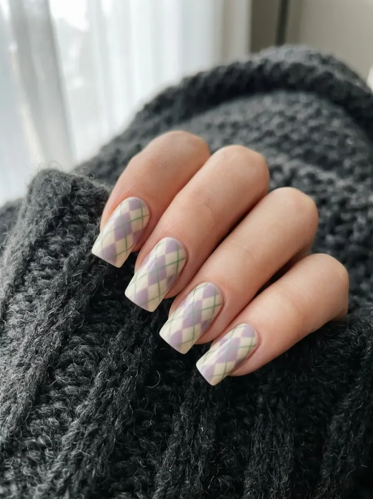 Soft pastel argyle nails in muted lilac and cream on a dark ground