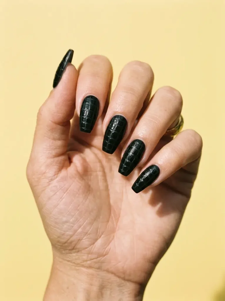 Medium coffin nails in matte black with a raised glossy crocodile skin texture, on a light skin tone