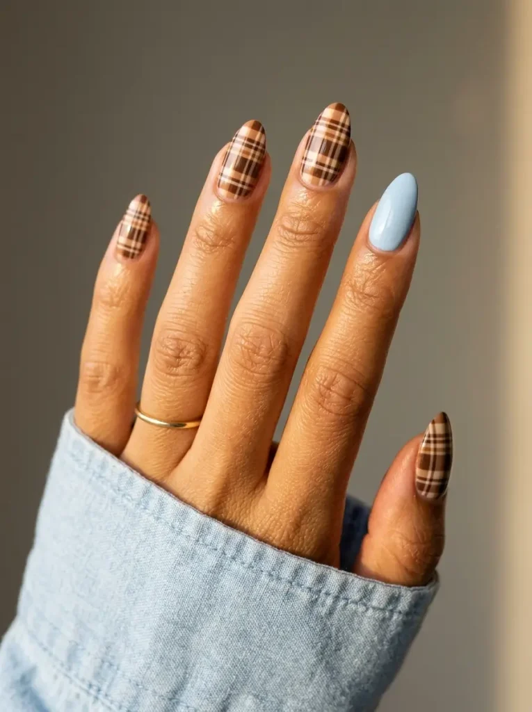 28 Fall Nail Designs for 2026, From Simple to Classy 28 Medium almond nails with brown and cream plaid on four nails and exactly one solid baby blue nail, on a medium skin tone