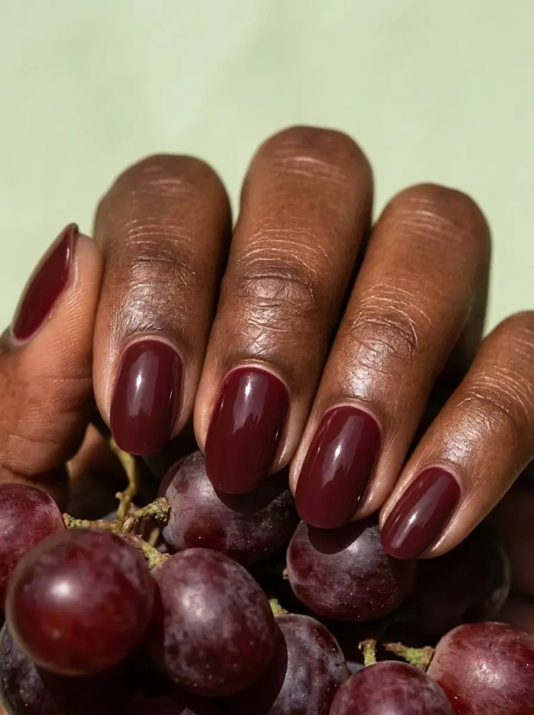 18 Fall Nail Colors for 2026, From Taupe to Navy 9 Burgundy wine red glossy oval nails of medium length, on a deep skin tone