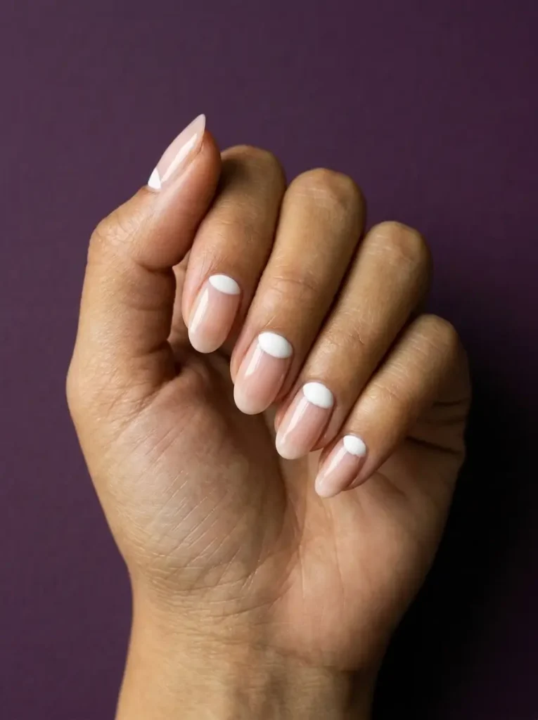 Medium oval sheer nude nails with a solid white half moon filled in at the cuticle of every nail, glossy finish, on olive skin