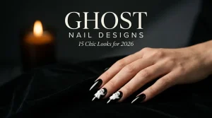 Ghost nail designs 2026 featuring glossy black stiletto nails with raised white ghost accents on a hand against a dark velvet background.