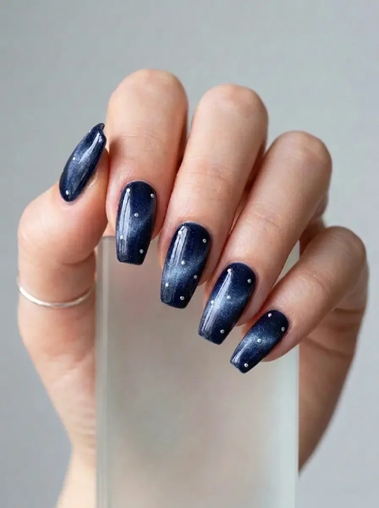 Medium coffin navy velvet cat eye nails with tiny scattered silver dots on every nail, on a fair skin tone