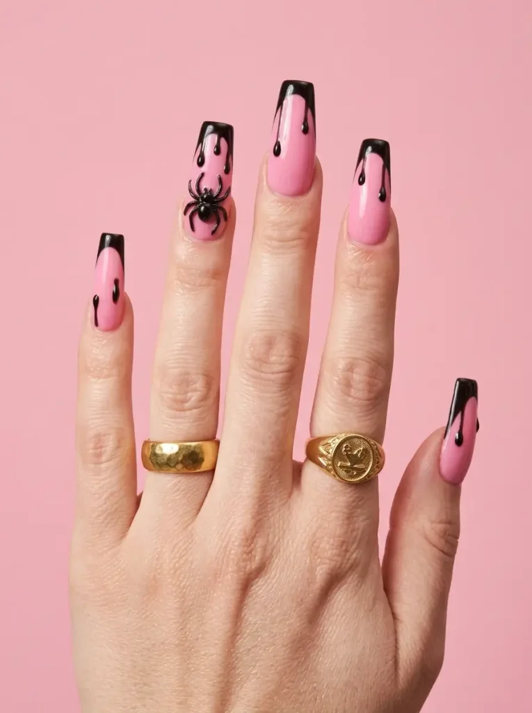 Long pink coffin nails with black tips, raised black drips and a 3D spider on the ring nail, on a fair skin tone