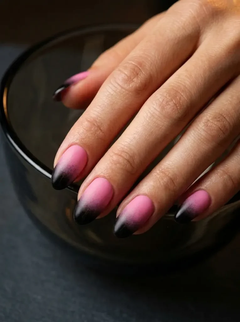 15 Pink Halloween Nail Designs for 2026, From Cute to Spooky 8 Oval nails in bubblegum pink fading to black over the top third of every nail, on a light skin tone
