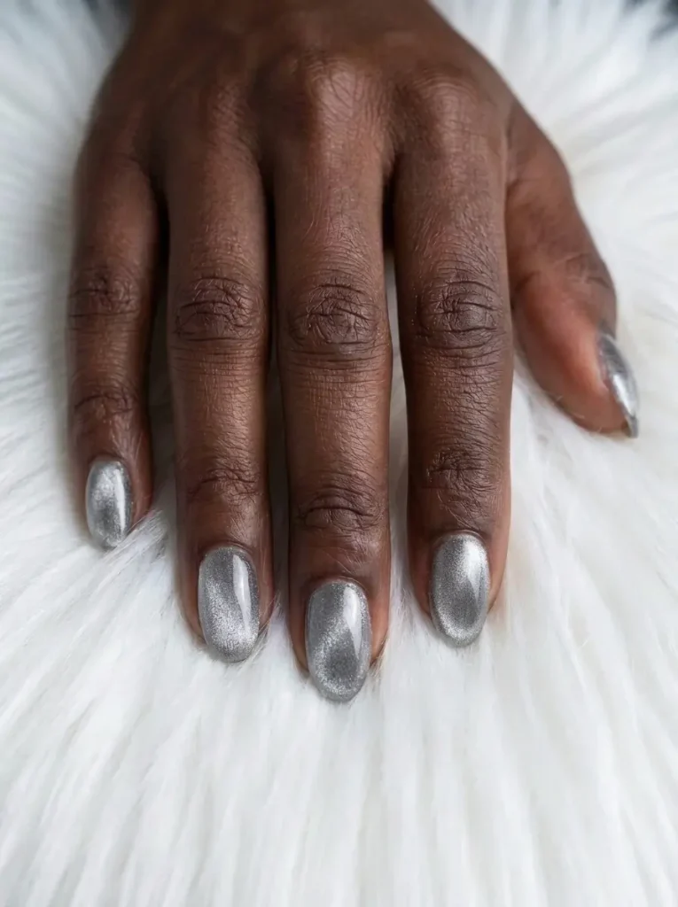 Medium oval silver velvet cat eye nails with an even frosted shimmer over every nail, on a deep skin tone