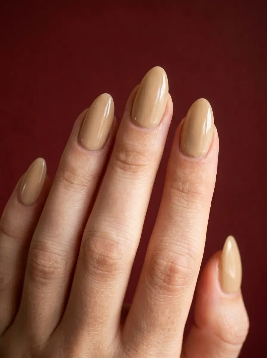 18 Fall Nail Colors for 2026, From Taupe to Navy 3 Warm beige glossy long almond nails, on a fair skin tone